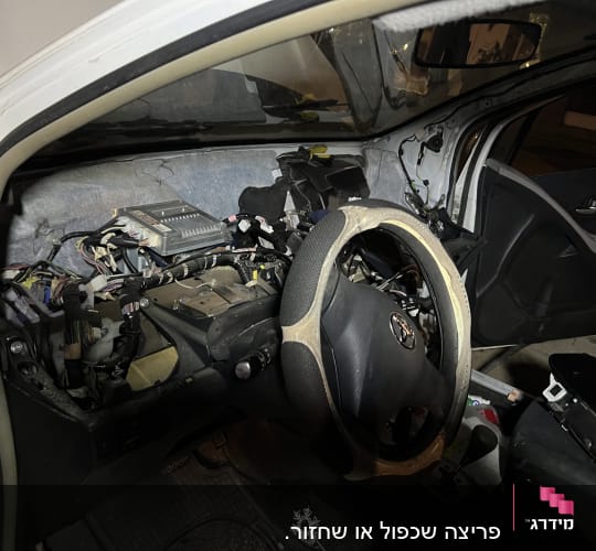 פנים רכב עם לוח מחוונים מפורק וחוטי חשמל חשופים